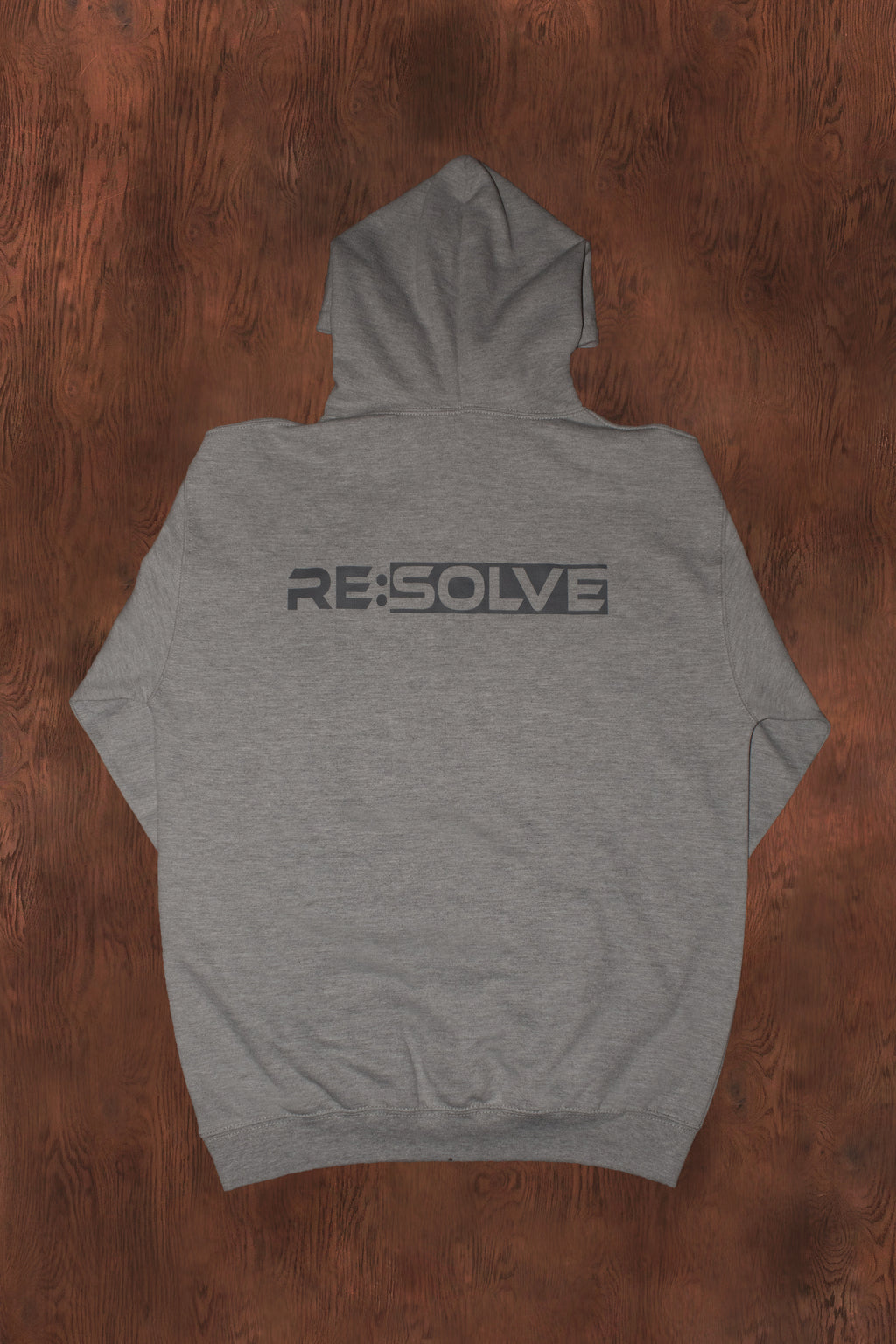 Gray hoodie with 'RE:SOLVE' logo on the back, placed on a wooden surface.