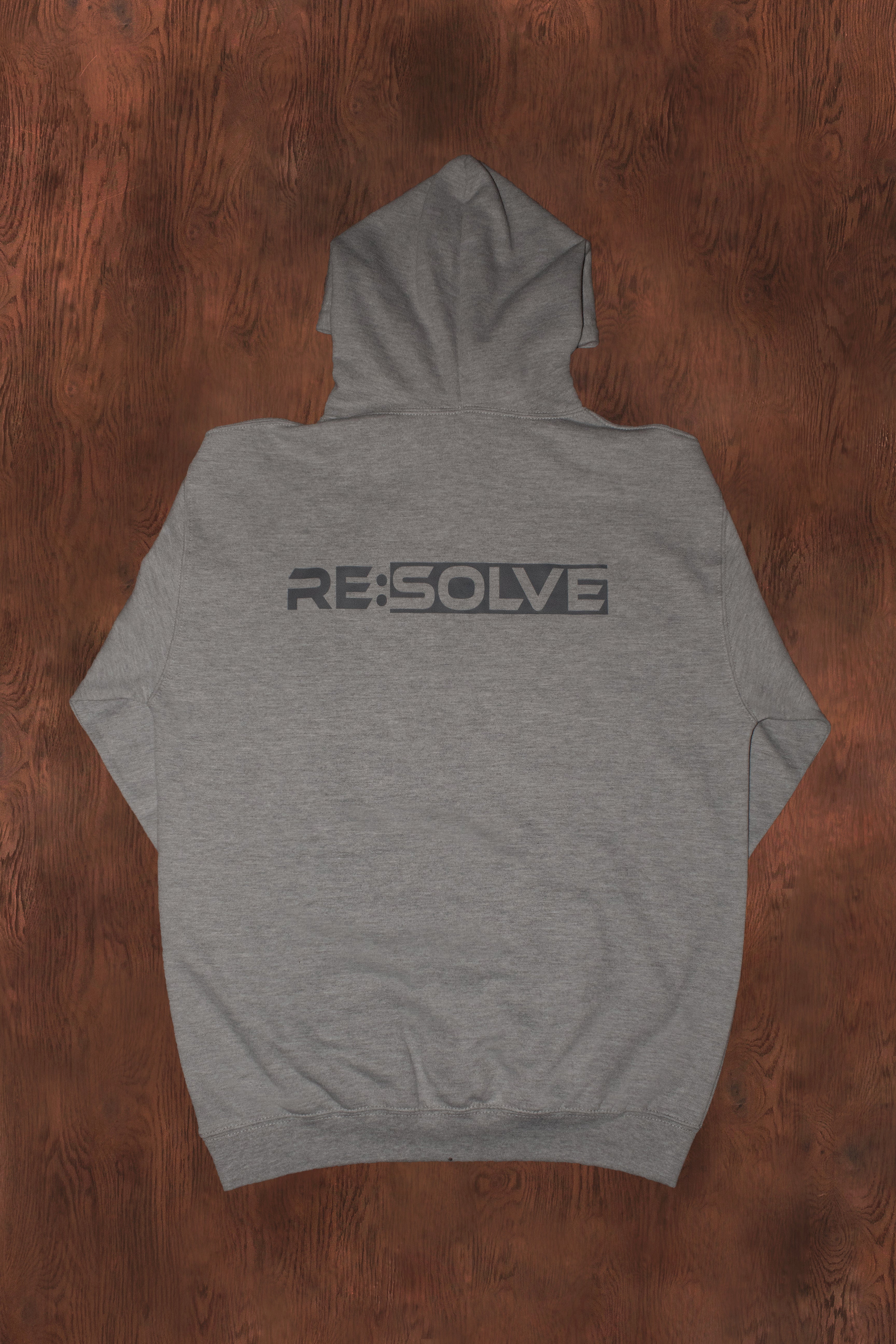 Gray hoodie with 'RE:SOLVE' logo on the back, placed on a wooden surface.